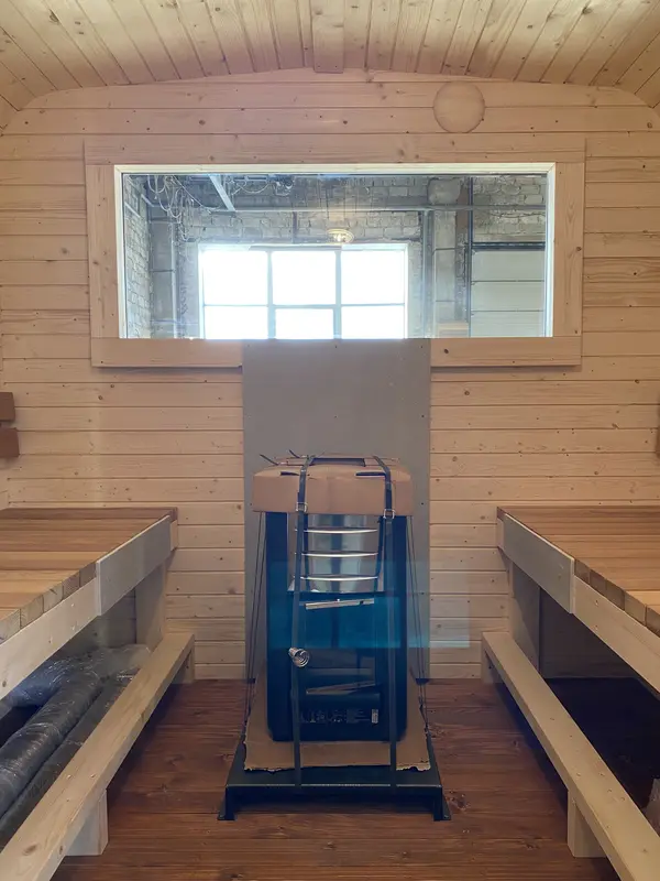 Intérieur d’un sauna cube 2 m avec poêle mural Scandic et banquettes latérales en bois.