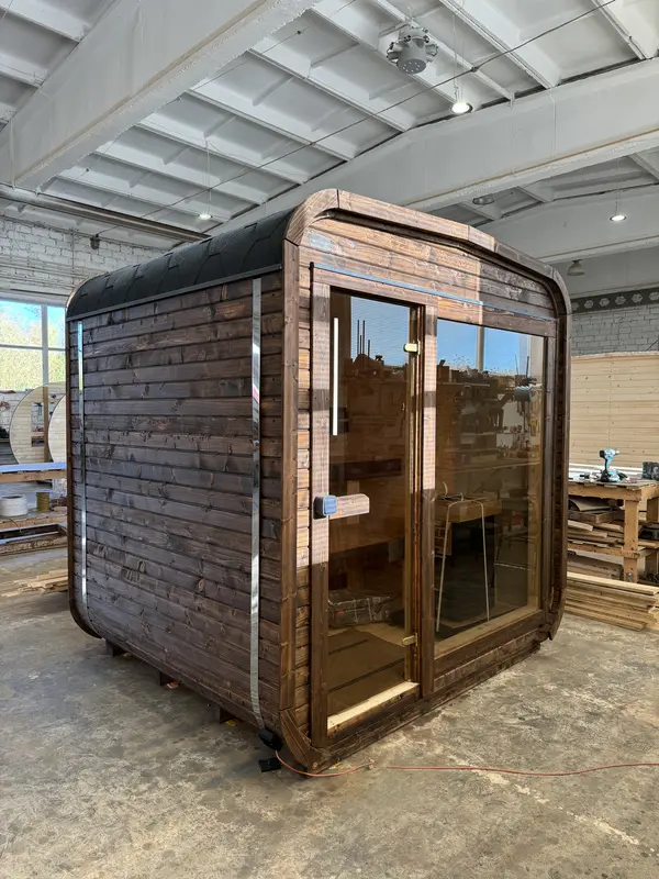 Sauna cube 2 m ThermoWood brun, vue d’angle avant avec double porte vitrée et toit arrondi.