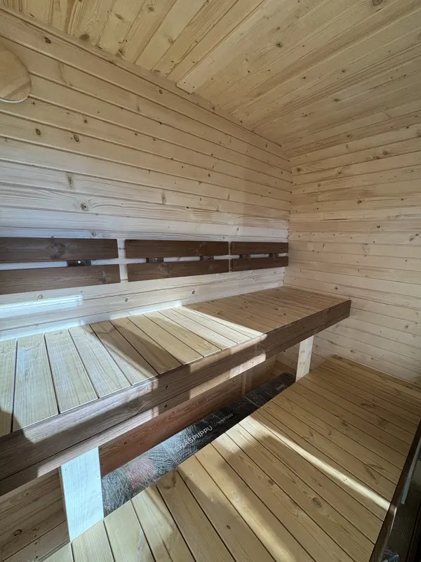 Intérieur d’un sauna cube 2 m montrant deux niveaux de banquettes en bois clair.