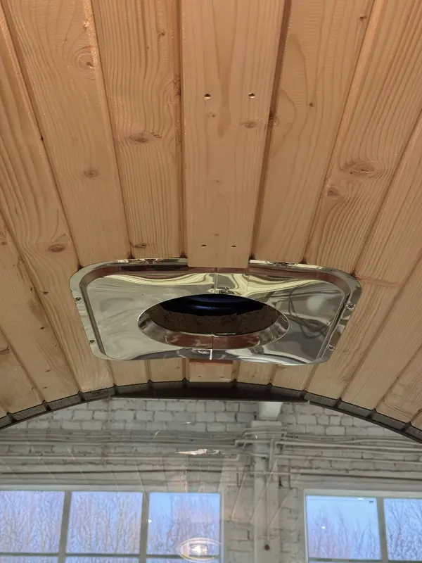 Sauna tonneau en bois vu de trois quarts, côté poêle