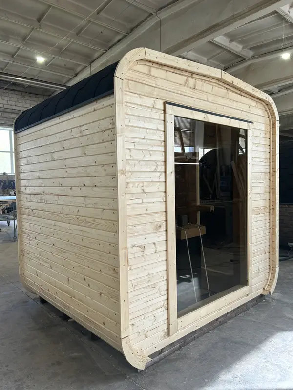 Vue extérieure d’un sauna cube 2 m en bois naturel, grand pare-vue vitré et toit acier.