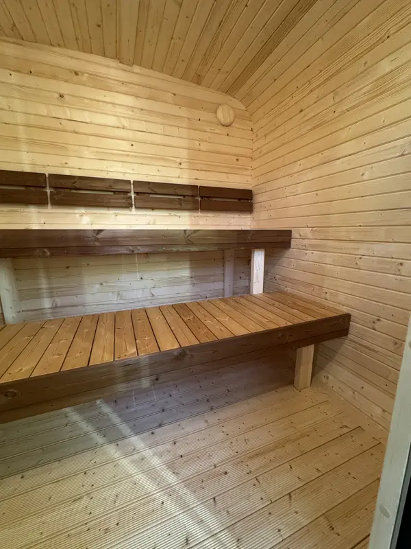 Intérieur d’un sauna cube 2 m montrant deux niveaux de banquettes en bois clair contre murs lambrissés