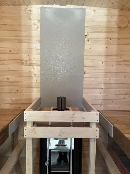 Intérieur d’un sauna cube 2 m avec poêle mural et garde-corps en bois clair, murs lambrissés