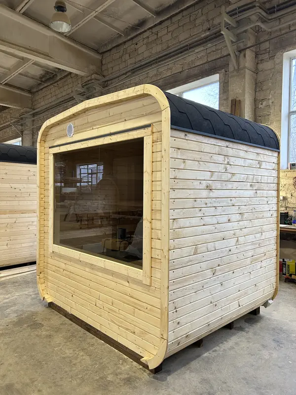 Sauna cube 2 m en bois naturel non traité, angle avant avec large fenêtre panoramique et toit arrondi.