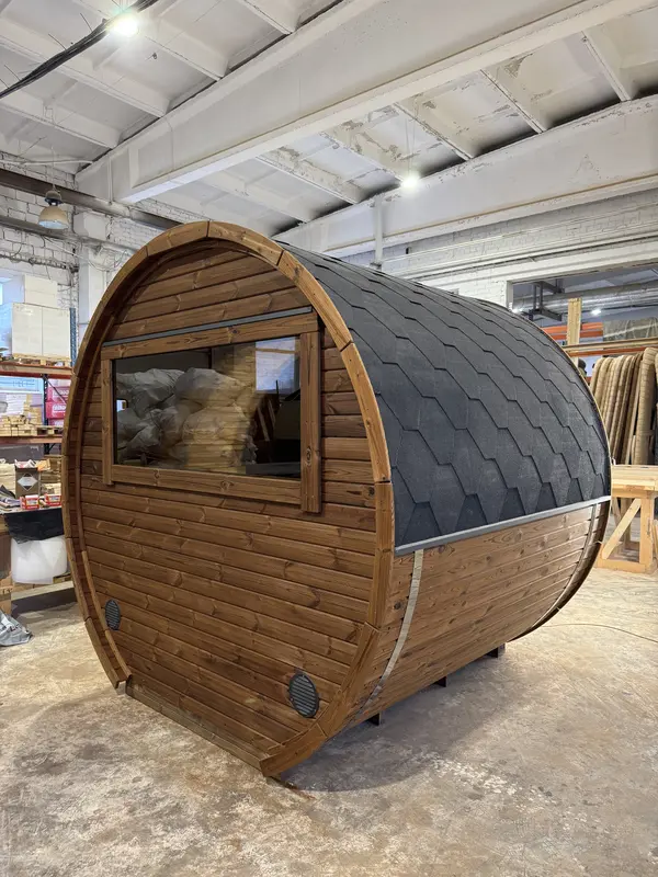 Intérieur du sauna tonneau montrant banquettes et espace poêle