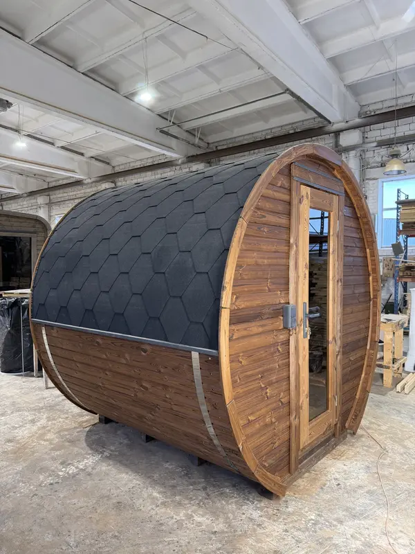 Sauna tonneau rouge foncé avec toit en bardeaux noirs, de côté