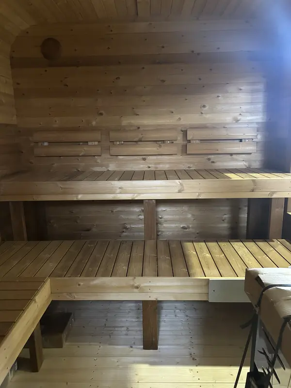 Intérieur d’un sauna cube 3 m Relax montrant deux niveaux de banquettes en bois naturel et mur lambrissé.