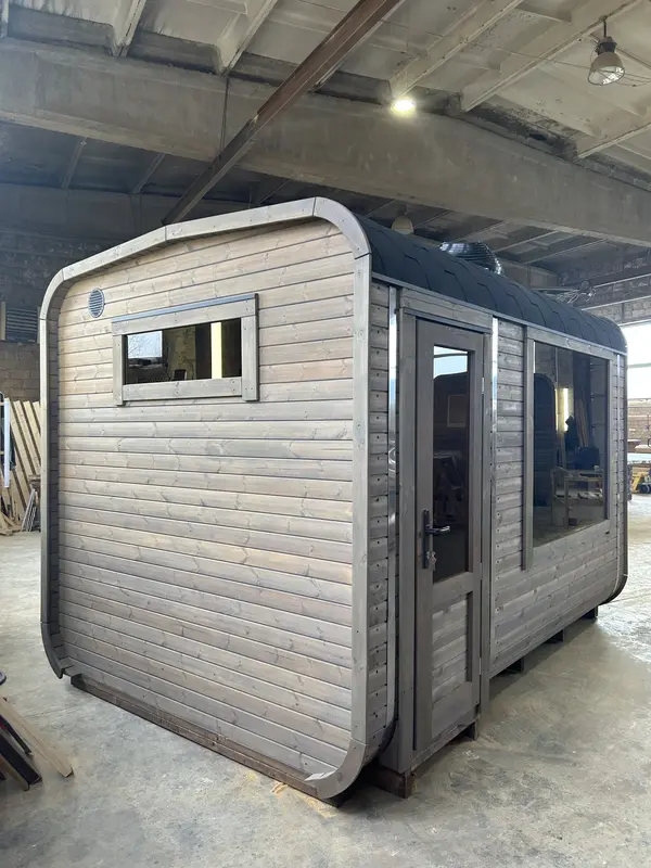 Sauna cube 3 m en bois naturel, avec petite fenêtre haute horizontale et porte vitrée.