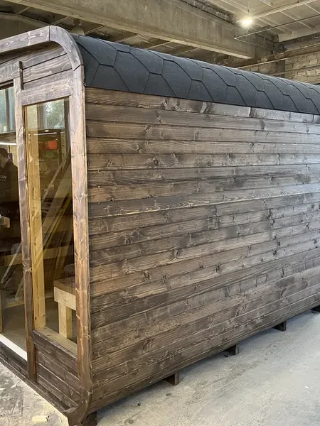 Sauna cube 3 m Relax peint en ThermoWood brun foncé, angle arrière montrant le bardage à lames horizontales.