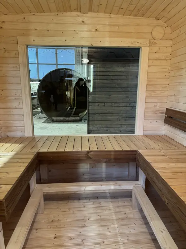 Intérieur de sauna cube montrant banquettes en bois clair formant un U et éclairage LED sous les lattes