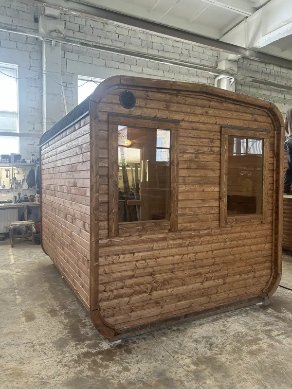 Angle arrière d’un sauna tonneau 3 m en Thermo brun, grande fenêtre latérale et bardage à lames horizontales.