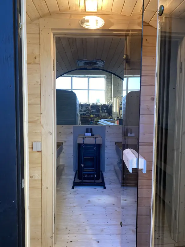 Intérieur du sauna tonneau 3 m Relax avec poêle Harvia posé au centre entre les banquettes
