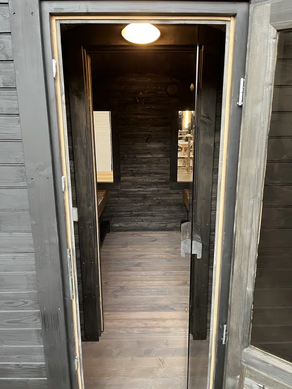 Couloir intérieur du sauna tonneau 3 m Relax, vue vers l’entrée avec sol en bois foncé