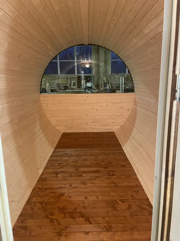 Intérieur du sauna tonneau 4 m, banquettes en bois clair et mur arrière en lambris