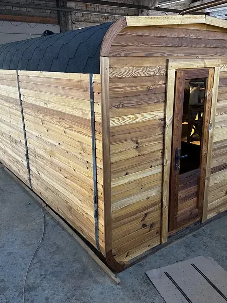Sauna cube 4 m en ThermoWood brun, vue d’angle avant avec porte vitrée et bardage horizontal