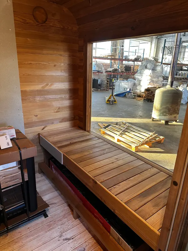 Intérieur d’un sauna cube 4 m montrant deux banquettes en bois clair et poêle mural