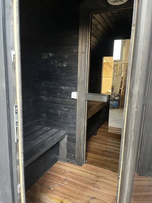 Détail intérieur du sauna tonneau 4 m : mur en lambris bois foncé et sol en mélèze