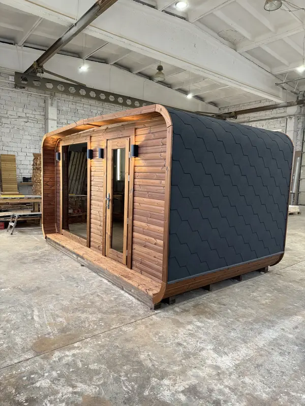 Vue d’angle d’un sauna 4 m de large en ThermoWood brun, toit arrondi noir et double porte vitrée.