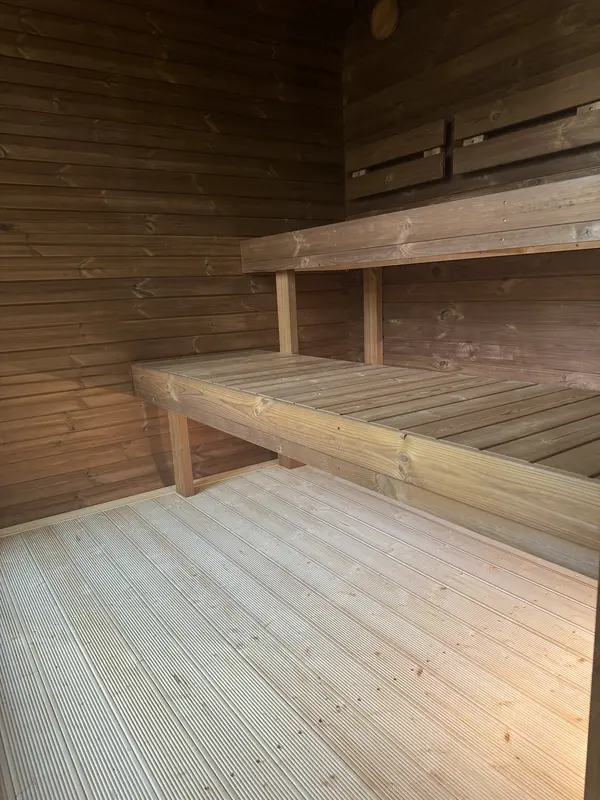 Intérieur d’un sauna 4 m large montrant banquettes en bois naturel et mur lambrissé clair.
