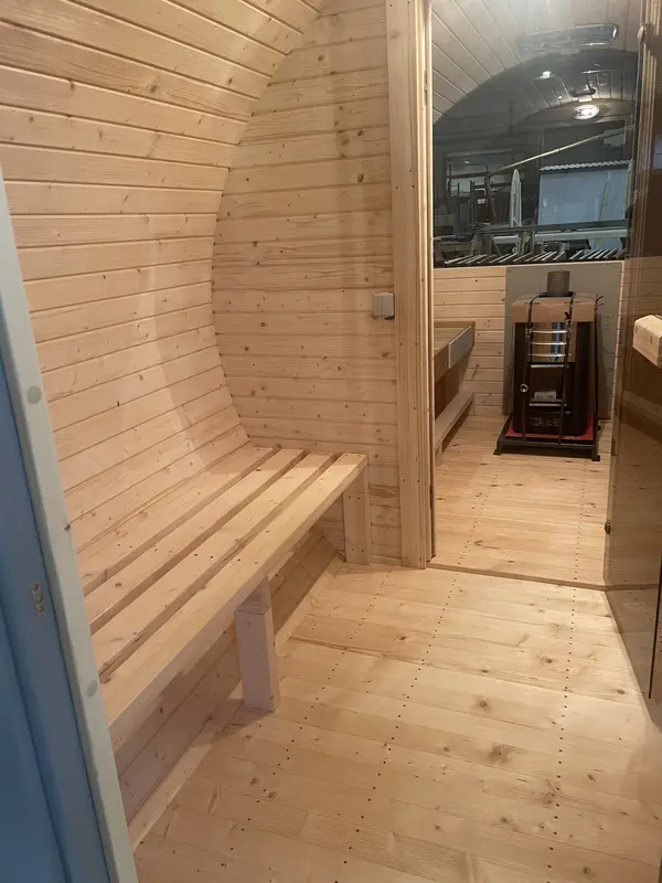Intérieur du sauna tonneau 4 m : banquettes en bois clair et poêle Harvia visible