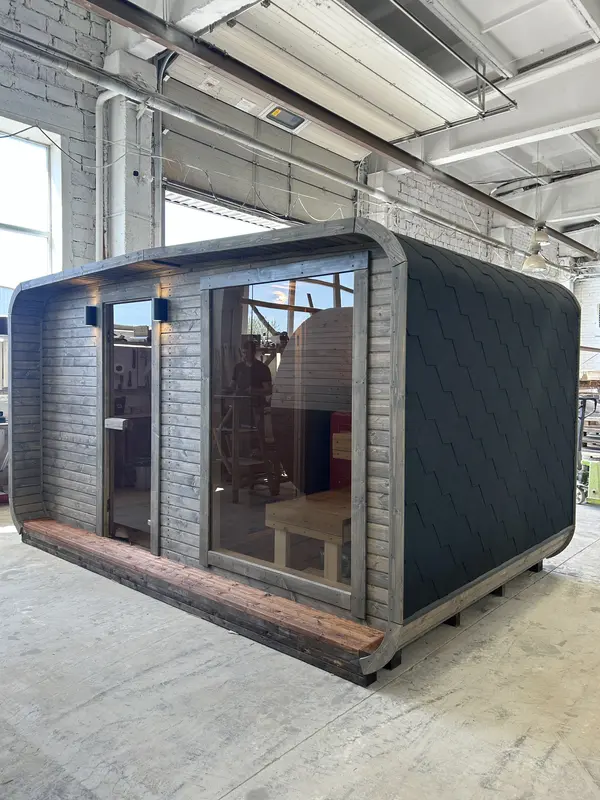 Vue d’entrée d’un sauna 4 m large noir avec banc extérieur intégré et intérieur éclairé visible.