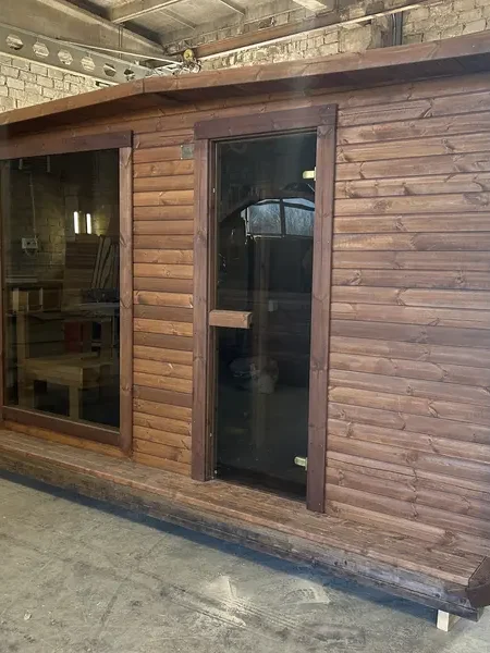 Closer view of the same: Sauna 4 m large ThermoWood brun, porte vitrée et baie panoramique latérale.