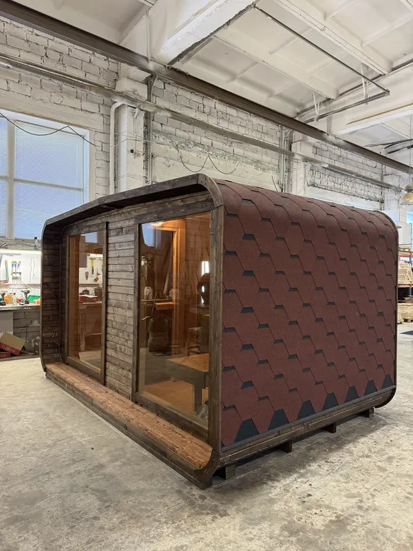Sauna 4 m de large vu de face, revêtement extérieur à motifs écaillés et double porte vitrée.