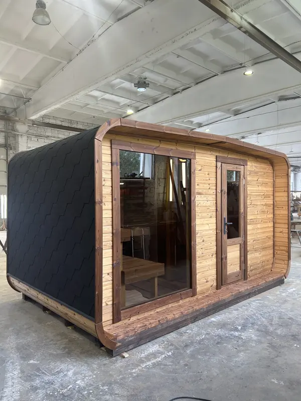 Profil extérieur d’un sauna 4 m large ThermoWood, bardage noir mat à motifs et cadre d’entrée en bois clair.