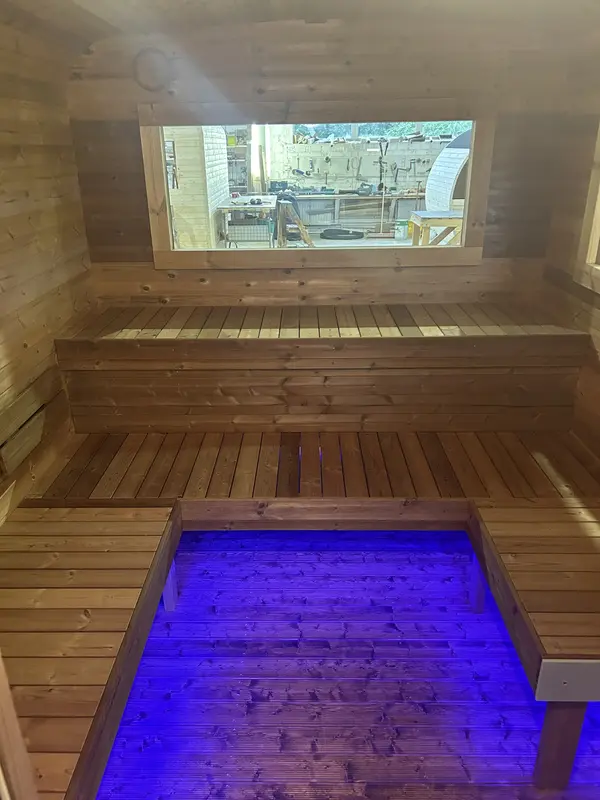 Banquettes intérieures d’un sauna cube 4 m éclairées par LED sous l’assise, lumière violette