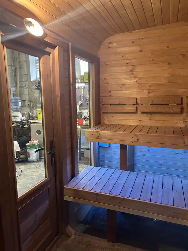 Intérieur d’un sauna cube 4 m, banquette en bois clair visible à travers la porte vitrée.