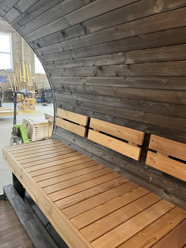 Banquettes en mélèze à l’intérieur du sauna tonneau 4 m, paroi arrière en bois foncé