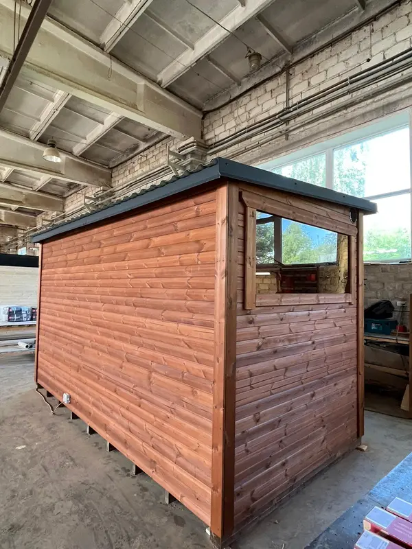 Vue latérale d’un sauna box 4 m en ThermoWood rouge, bardage à lames horizontales et toit en acie
