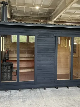 Autre vue frontale d’un sauna box 4 m noir, double vitrage laissant entrevoir les banquettes en bois.