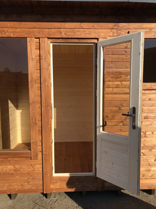 Gros plan sur une porte de sauna box ouverte, intérieur lambrissé clair visible.