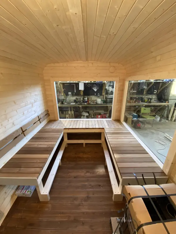 Couloir central d’un sauna cube 5 m Relax, banquettes de chaque côté et fenêtre frontale.