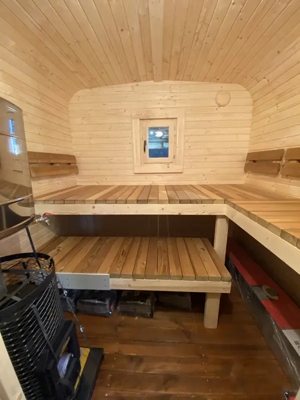 Intérieur d’un sauna cube 5 m Relax, banquettes en U contre murs lambrissés clairs et petite fenêtre frontale.