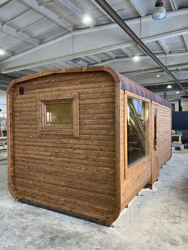 Sauna cube 5 m Relax brun foncé, vue d’angle arrière avec grande fenêtre panoramique latérale.