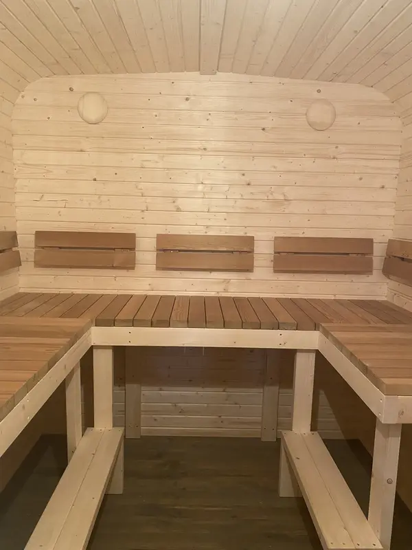 Intérieur d’un sauna cube 5 m, banquettes en angle formant un L contre murs lambrissés clairs.
