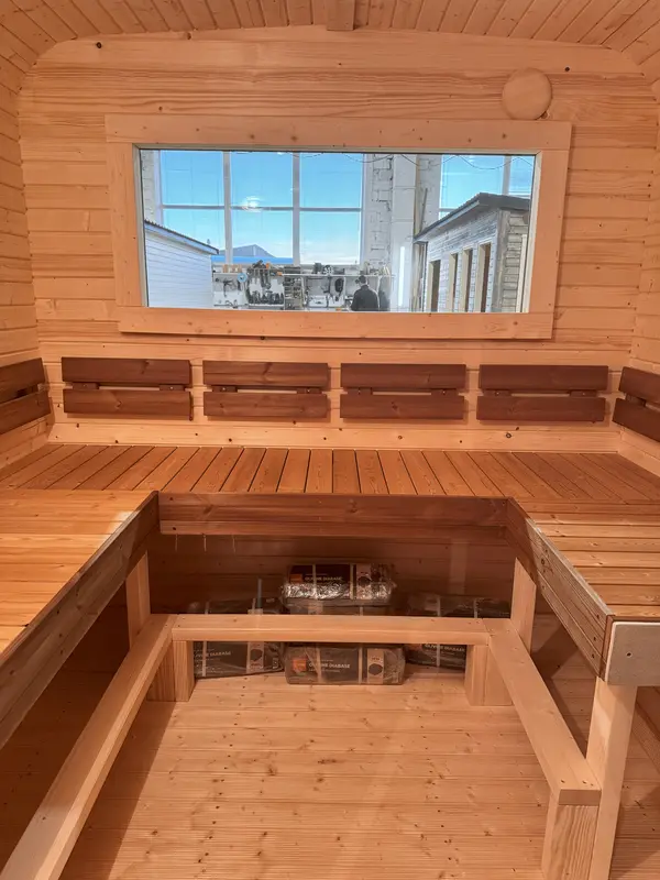 Deux niveaux de banquettes en bois naturel dans l’intérieur d’un sauna cube 5 m, vue plongeante.