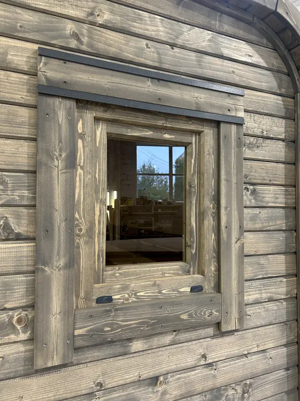 Gros plan sur le cadre de la fenêtre d’un sauna cube 5 m en ThermoWood gris, style rustique.