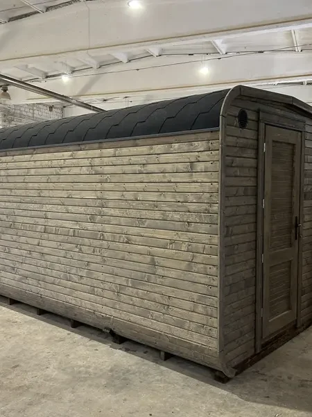 Vue latérale d’un sauna cube 5 m ThermoWood gris, bardage horizontal et fenêtre panoramique.