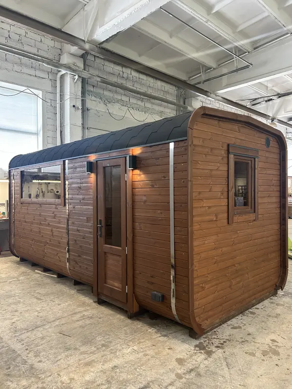 Vue latérale d’un sauna cube 5 m en bois Thermo brun, porte vitrée et grand vitrage latéral.