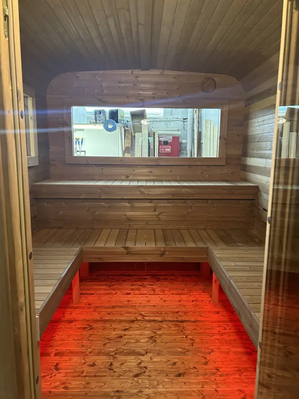 Banquettes intérieures d’un sauna cube 5 m éclairées par un ruban LED rouge sous l’assise.
