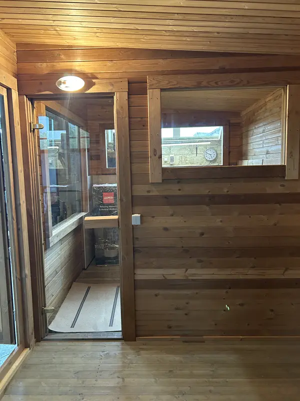 Détail intérieur d’un sauna box 5 m, deux niveaux de banquettes en bois naturel éclairées par une fenêtre latérale.