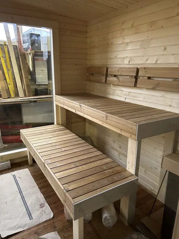 Intérieur d’un sauna box 5 m montrant deux niveaux de bancs en bois clair adossés à un mur lambrissé.