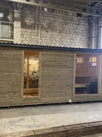 Sauna modulable 5 m en ThermoWood gris vieilli, double vitrage et porte vitrée, en hangar.