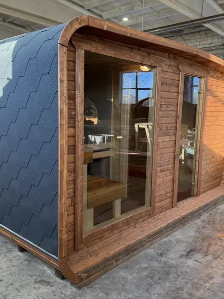 Profil latéral d’un sauna 4 m large en ThermoWood brun, bardage à motifs écaillés noirs et cadre bois clair.
