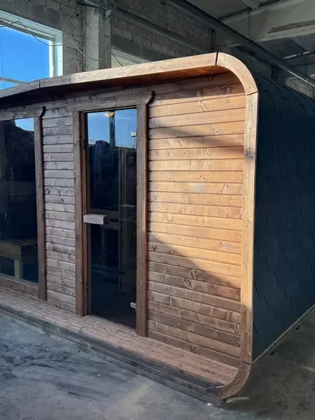 Sauna 4 m large en ThermoWood brun, vue avant avec double porte-vitrée sous un cadre arrondi noir.