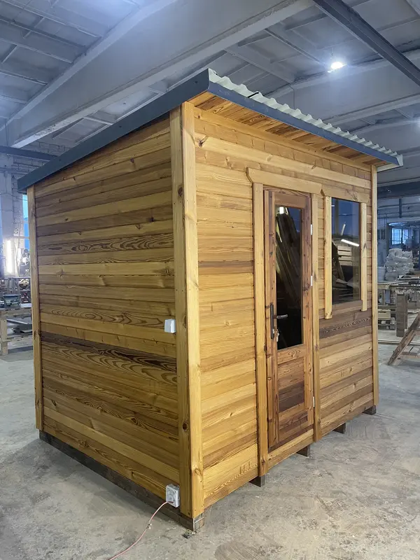 Angle avant d’un sauna « L » en bois naturel, double porte vitrée et grande fenêtre latérale.