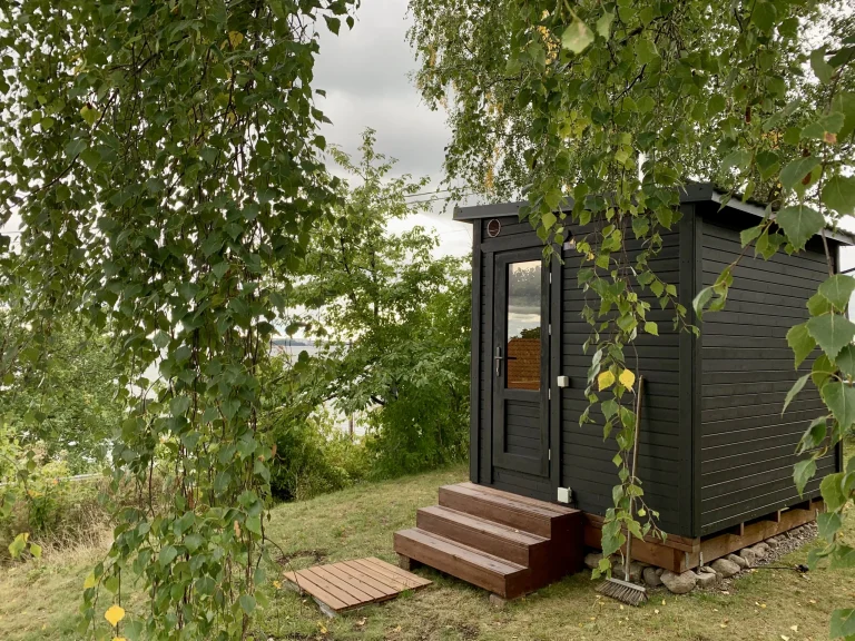 Sauna modulable en configuration L ThermoWood brun foncé, vue d’angle extérieur avec grandes baies vitrées